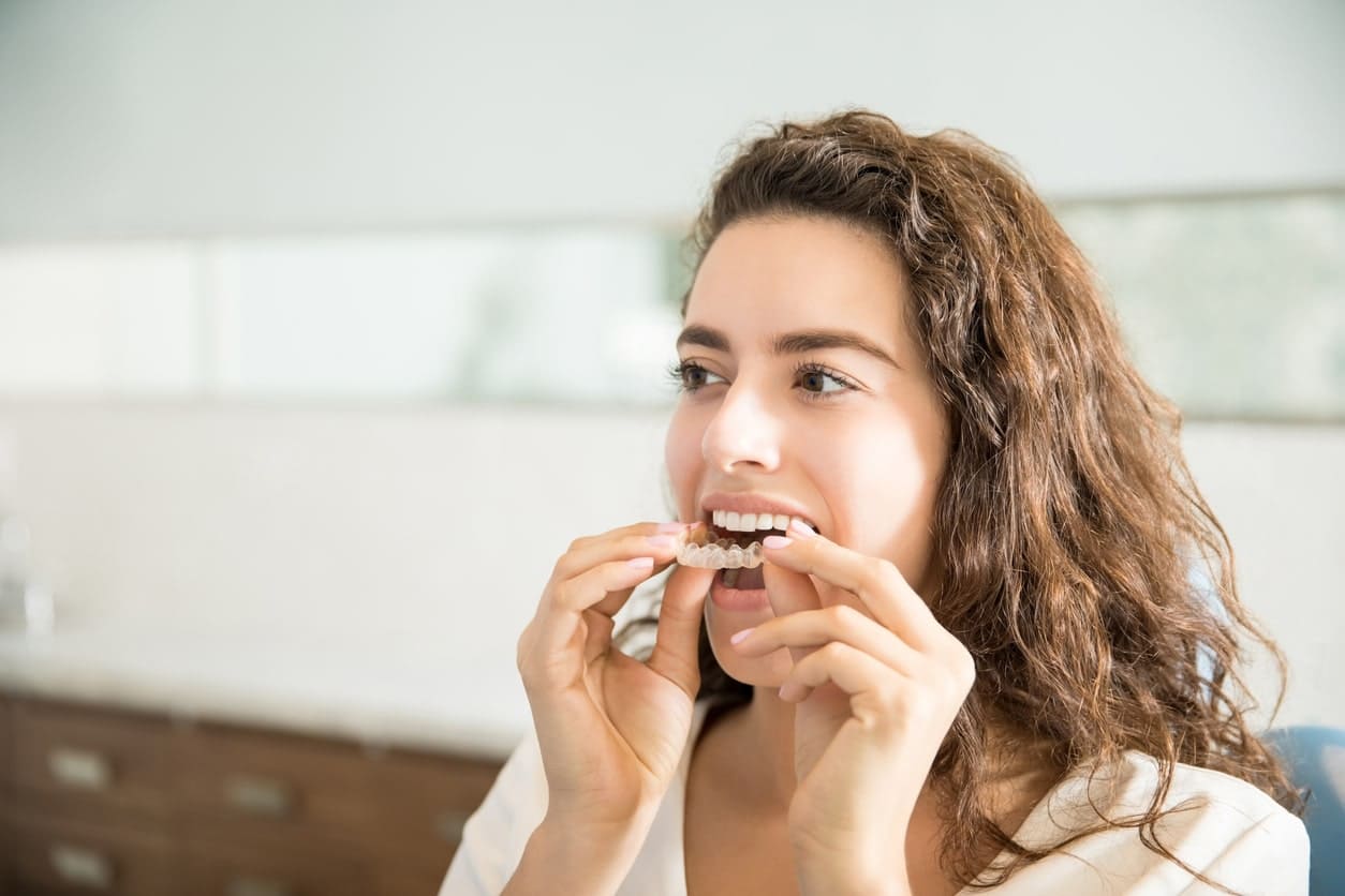 woman inserting her invisalign braces